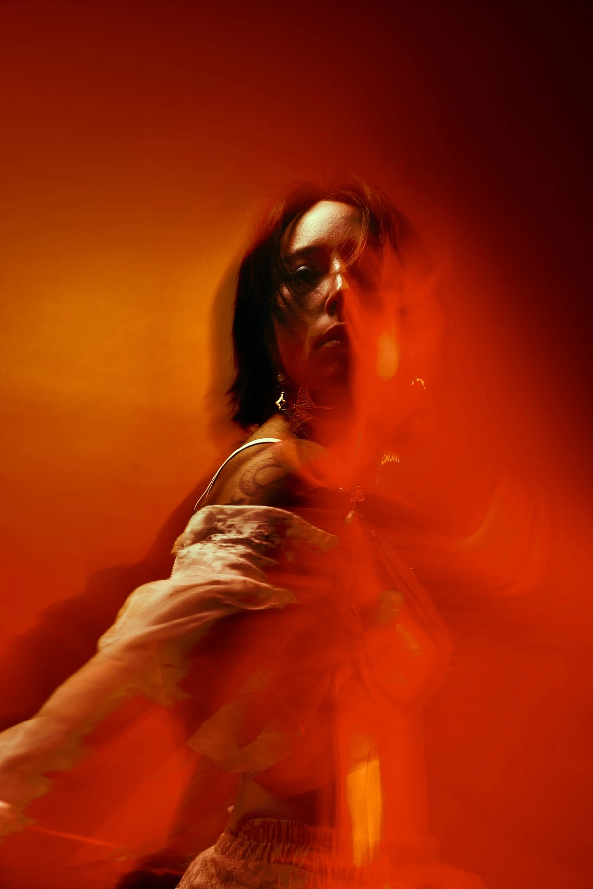 Portrait flou en mouvement de Maeva baignée de lumière rouge et orange, effet de pose longue
